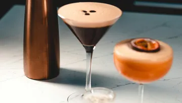 Cocktails stehen auf einem Tisch, bronze Shaker daneben.