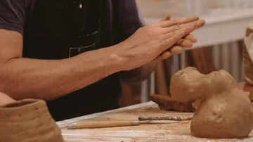 Hände formen Ton in einem kreativen Atelier.