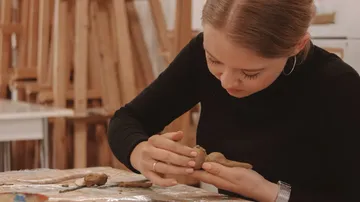 Junge Frau formt Ton in einem kreativen Atelier.
