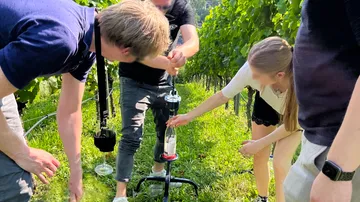 A group opens a bottle in the vineyard.