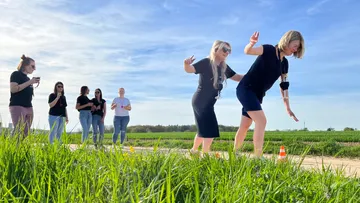 Frauen balancieren auf einer Strecke, umgeben von Wiese.