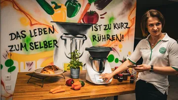 Küchenmaschine steht auf Tisch, Bedienung und Präsentation erfolgen.