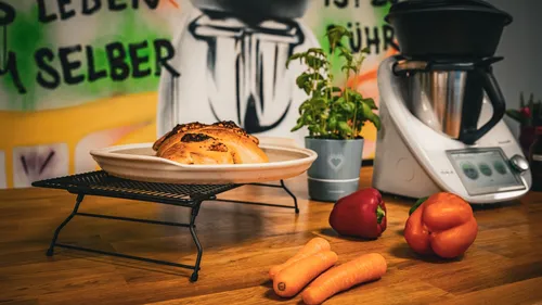 Bread on a rack surrounded by vegetables in the kitchen.