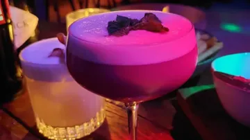 Ein bunter Cocktail steht auf einem Tisch in einer Bar.