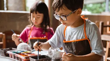 Children paint with paint on pottery in a workshop.