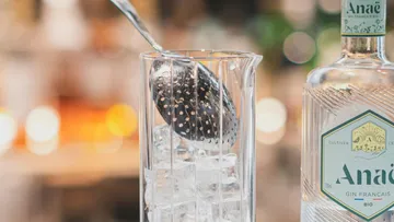 Eis wird mit einem Sieb in ein Glas gefüllt.