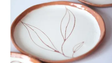 Ceramic plate with plant motif is lying on the table.