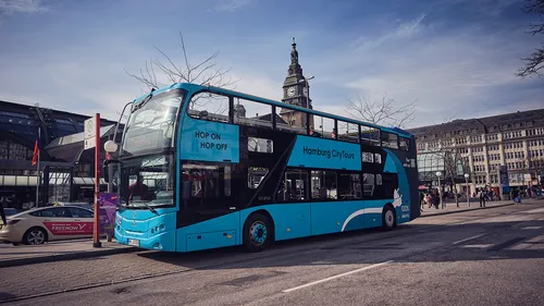 A double-decker bus stops on a city street in Hamburg.