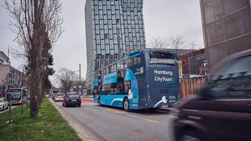 A double-decker bus travels through an urban area in Hamburg.