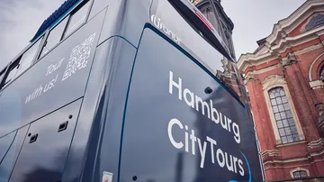 Double-decker bus promotes Hamburg city tours in front of historic architecture.