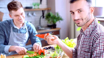 Zwei Männer bereiten gemeinsam frisches Gemüse in der Küche vor.