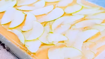 Eine Tortenschicht mit grünen Apfelscheiben und gelatem Belag.