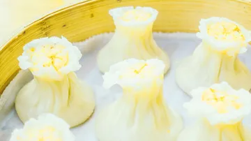 Steamed dumplings in a bamboo steamer are presented.