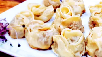 Steamed noodles lie on a white plate in a presentation.