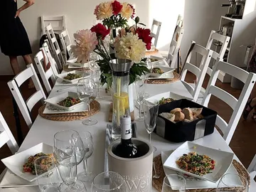 Tisch mit gedecktem Essen und Blumen in heller Umgebung.