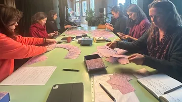 Frauen sortieren Karten an einem Tisch in einem Raum.