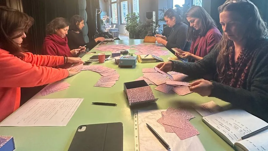 Women sort cards at a table in a room.