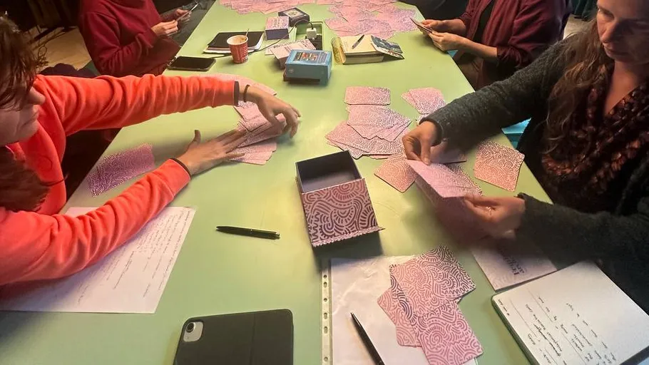 Mehrere Personen sortieren bunte Karten an einem Tisch.