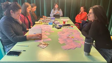 Frauen sitzen mit Karten an einem Tisch.