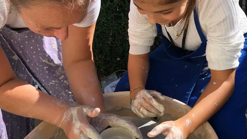 Zwei Personen formen gemeinsam Ton auf einer Töpferscheibe.
