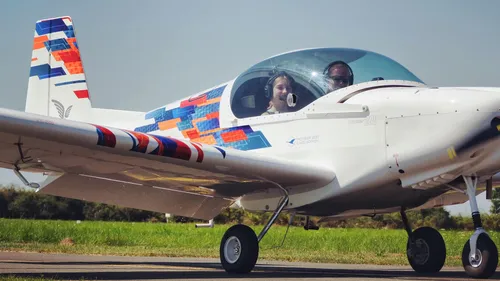 A colorful plane is parked on the runway, passengers are sitting in it.