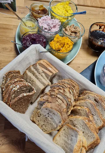 Ein Korb mit Brotscheiben steht neben verschiedenen Aufstrichen.