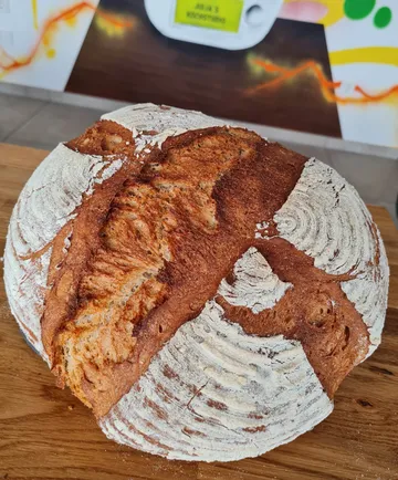 Runder Brotlaib liegt auf einem Holzbrett, frisch gebacken.