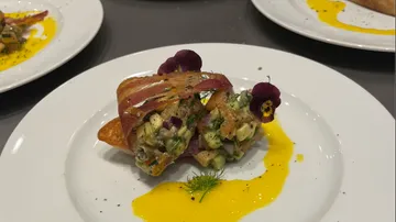 Filled dough roll on plate, garnished with flowers.