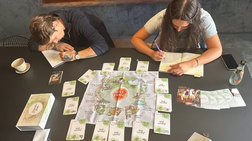Zwei Personen spielen ein Brettspiel an einem Tisch.