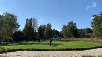 Mensch spielt Golf auf einem Rasenplatz im Freien.