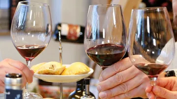 Gläser mit Rotwein werden bei Snacks angestoßen.