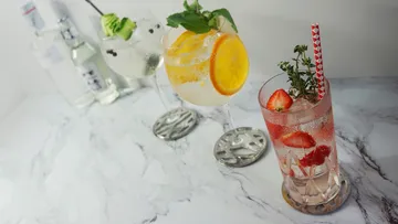 There are three cocktails on a marbled table.