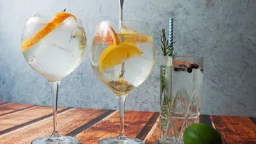 Drei Cocktails stehen auf einem Holztisch, frisch zubereitet.