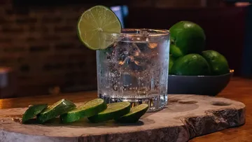 Ein Glas mit Getränk, Limettenscheibe und geschnittenen Limetten.