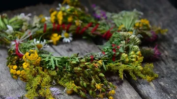 A colorful wreath of flowers is lying on a wooden table.