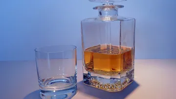 A glass carafe with a golden drink next to an empty glass.