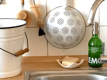 Küchenspüle mit Seife, Bürsten und Metallsieb.