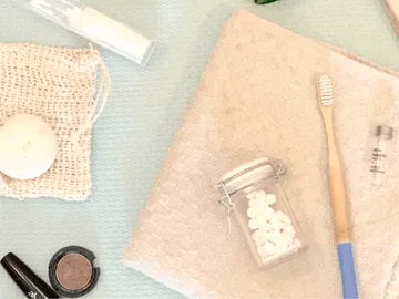 Zahnbürste liegt auf einem Handtuch neben weiteren Gegenständen.