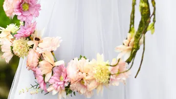 A wreath of flowers hangs on a white dress in nature.
