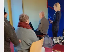 Menschen sitzen auf Stühlen, während eine Person spricht.