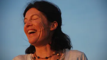 Lächelnde Frau genießt das Sonnenlicht am Abendhimmel.