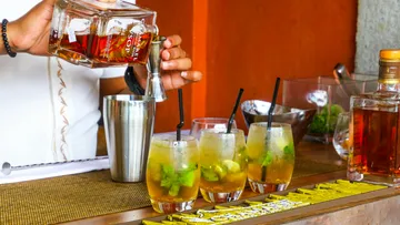 Ein Barkeeper gießt Getränke in Gläser auf der Theke.