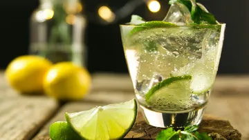 Glass with drink, mint and lime on wooden table.