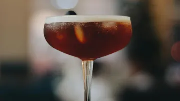 Ein Cocktail in einem eleganten Glas steht im Vordergrund.