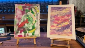Two paintings stand on stands in a bar.