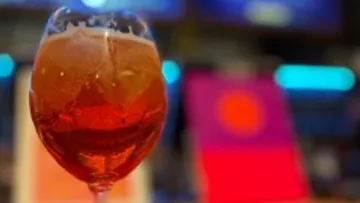 Red brown drink in a glass, background with colorful lights.