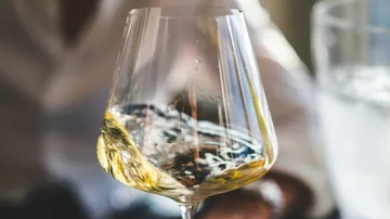 Weißwein im Glas schwenkt, um das Aroma freizusetzen.