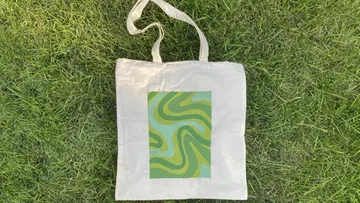 A fabric bag is lying on green grass and shows patterns.