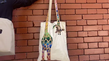 Fabric bag with colorful design hangs on brick wall
