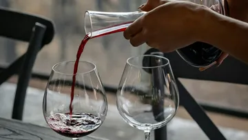 Wine glass is filled with red wine in a restaurant.